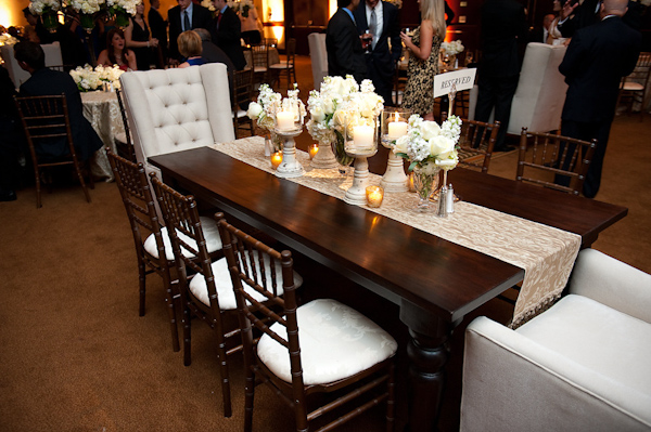 reception seating -long dark brown table with white floral centerpieces and yellow and ivory candles -photo by Houston based wedding photographer Adam Nyholt